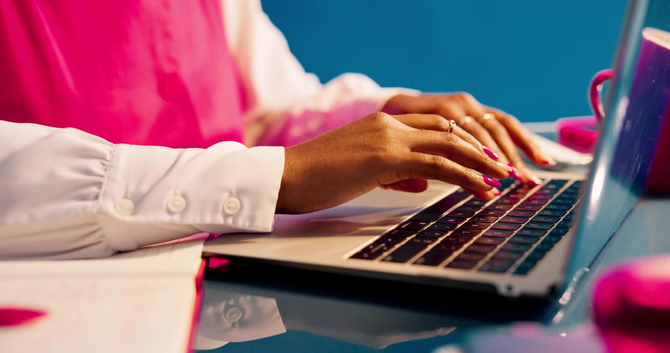 Primo piano di una donna che digita sul laptop in uno studio dai colori vivaci