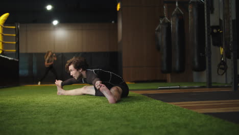 Young-sport-man-doing-splits-at-gym.-Male-boxer-making-stretching-in-sport-club