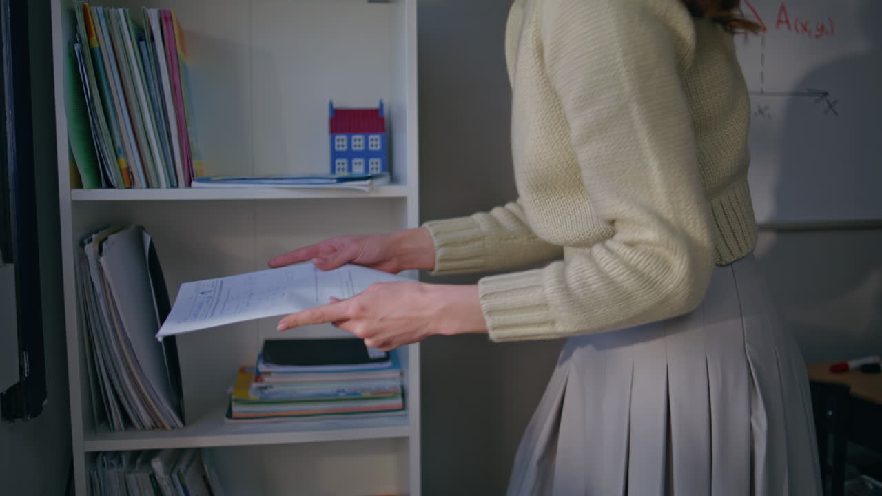 School teacher taking folders from shelf closeup. Young woman checking homework