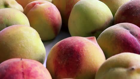 hand of a lady is picking up the peach from the row in the basket