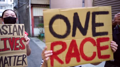 asian protesters in face masks with placards on city street