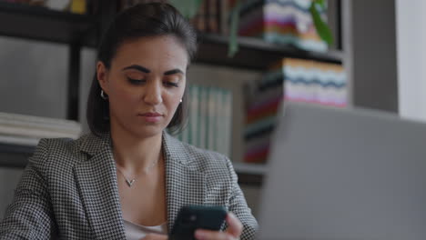 Indian-hispanic-woman-spend-free-time-using-internet-social-media-network-website-read-multimedia-news.-Business-arabian-lady-is-chatting-on-mobile-phone-and-working-with-laptop-indoors-in-apartment.