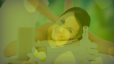 recibiendo masaje, mujer sonriendo sobre velas y decoraciones de spa