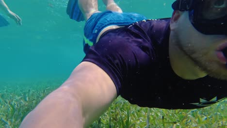 a male snorkeller with a shirt on swims in the clear waters off hol chan marine reserve, san pedro, belize