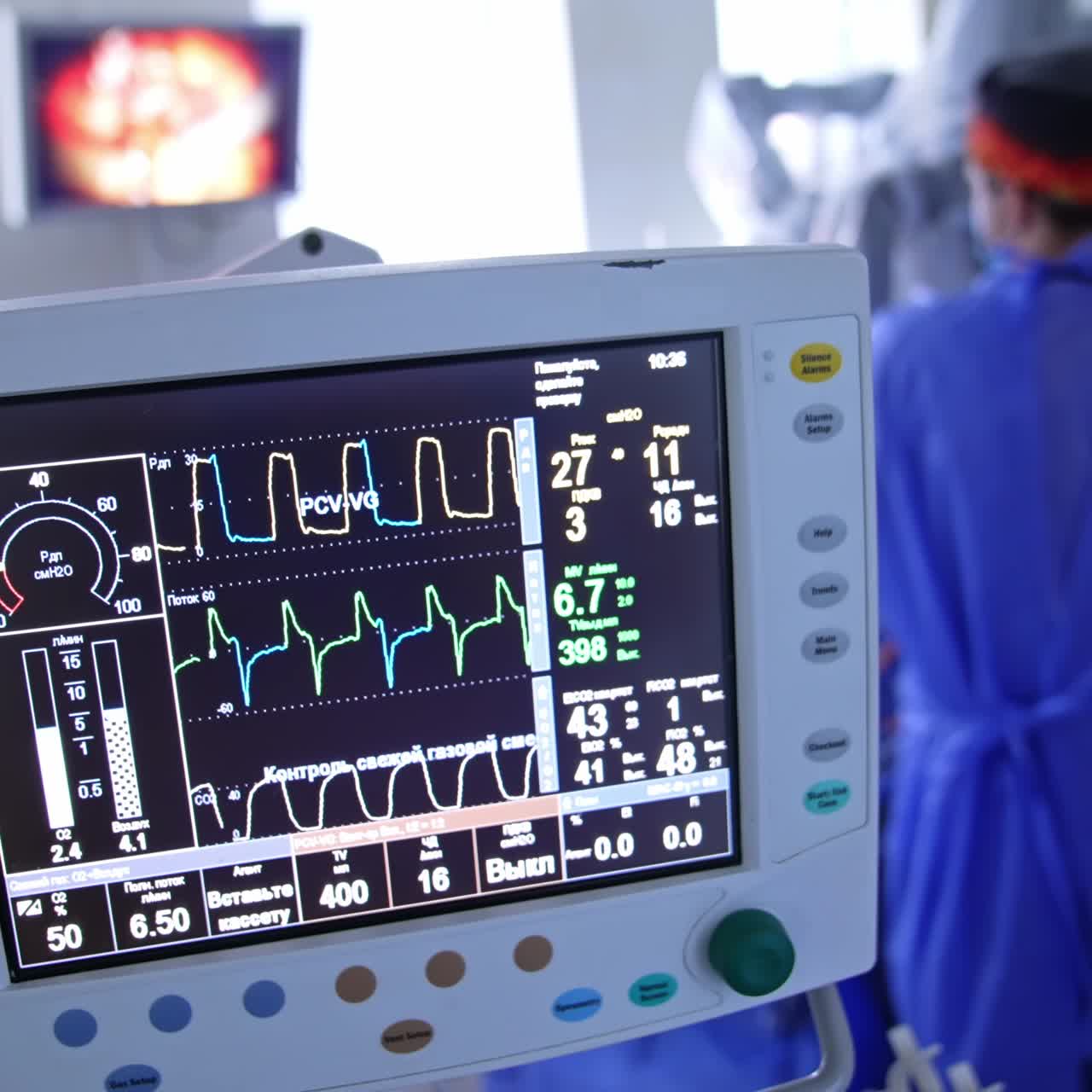 Screen with life parameters of patient under operation. Rear view of a doctor standing near Da Vinci robot. Blurred backdrop