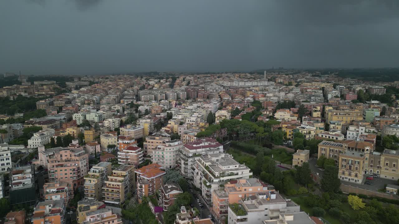 Vorwärtsfliegende Drohnenaufnahme von dunklen Wolken, die an einem stürmischen Tag über Wohngebäuden in Rom, Italien, vorbeiziehen.