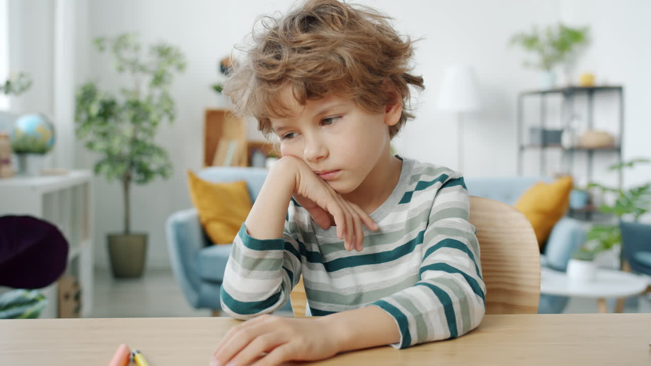 Bambino triste seduto al tavolo