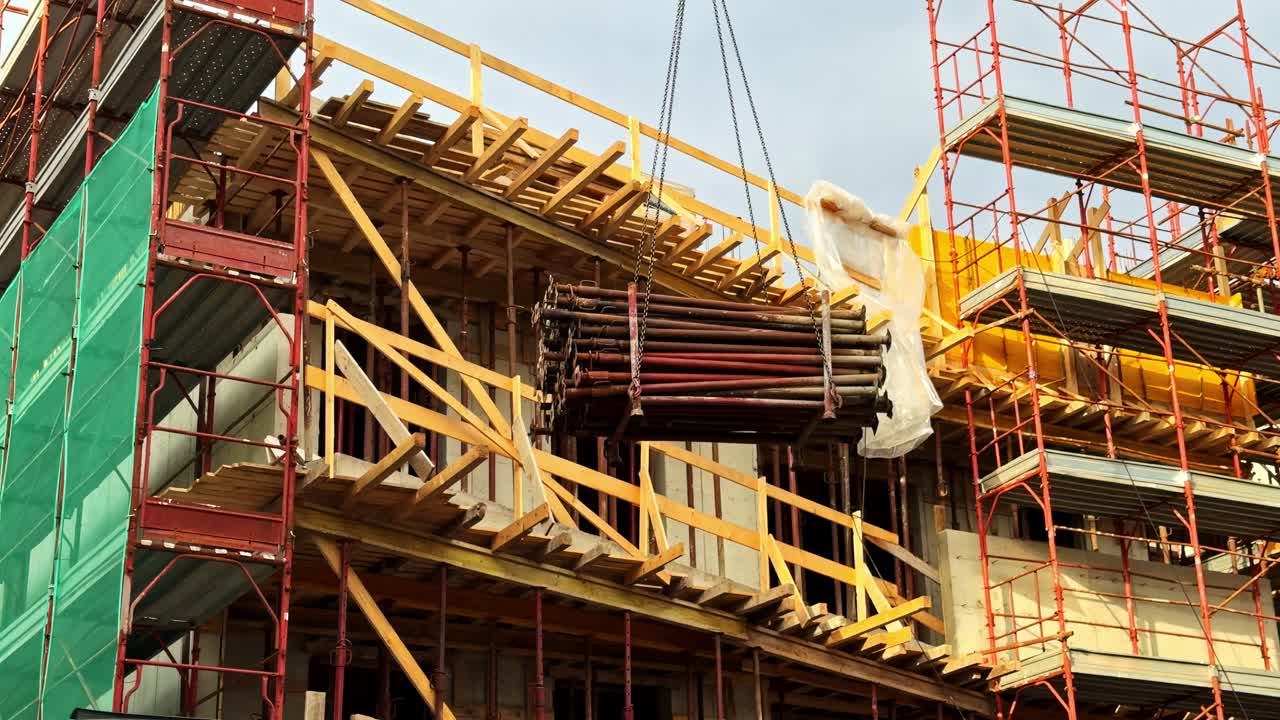 Construction site with scaffolding up, crane moving structural elements up
