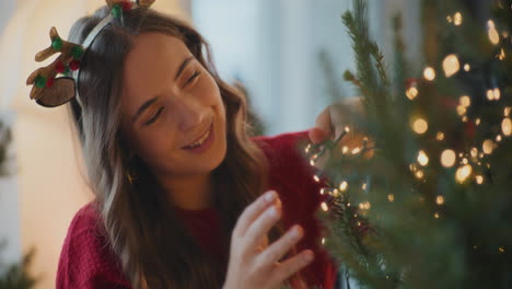 mujer ajustando las luces de led iluminadas en el árbol