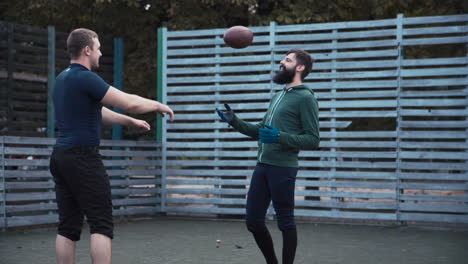 two men on a field with a football, possibly training or playing