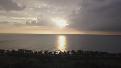 View-Of-A-Dramatic-Sunset-With-Dark-Clouds---Beautiful-Sunset-Over-The-Sea-In-Rajbagh-Beach,-Canacona,-South-Goa,-India---aerial-drone-shot