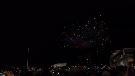 Lots-of-fireworks-taking-place-from-a-building-top-in-an-urban-night-sky