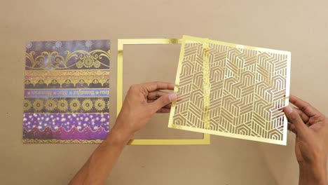 decorated ornate paper and gold foil page frames laid on desk