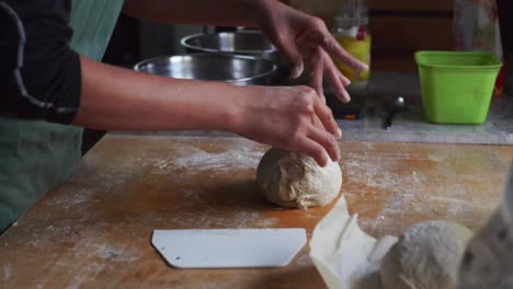 fresh dough roll being plucked by hands of chef on kitchen tabletop, filmed as medium closeup slow motion shot