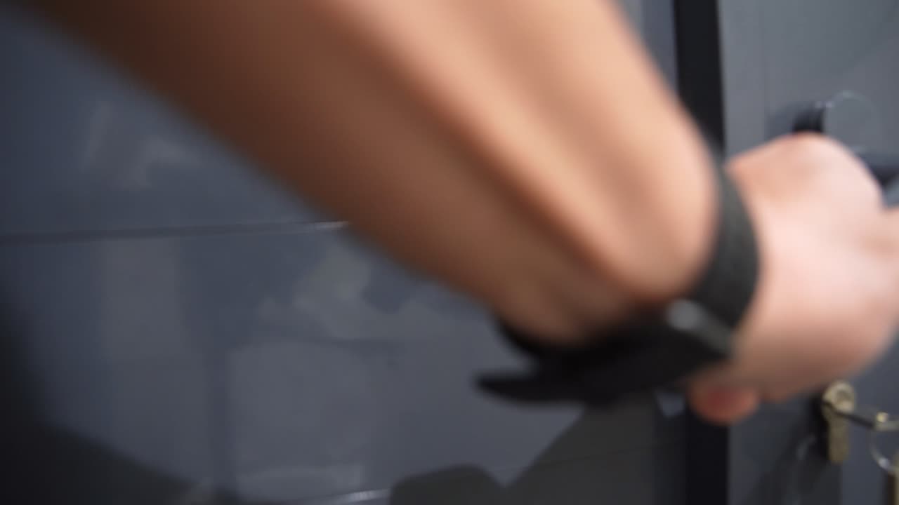 Close-up of hand unlocking gray door with a key. Perfect for security, privacy, or facility access scenarios.