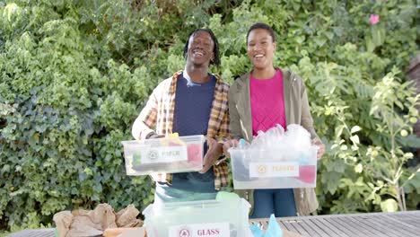 Portrait-of-happy-african-american-couple-collecting-recycling-in-sunny-garden,-slow-motion