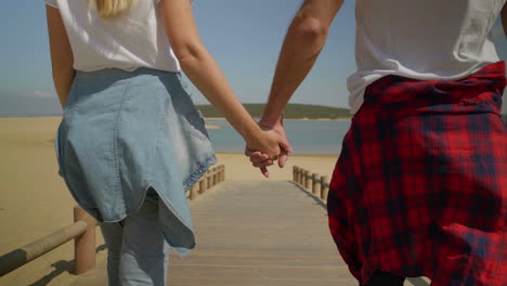 Cropped-shot-of-couple-holding-hands-and-walking-on-beach