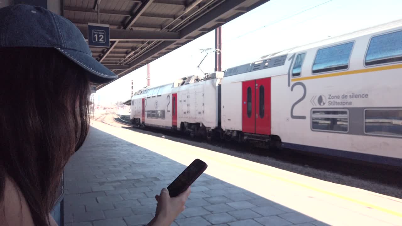 Woman waits as Belgian train passes by platform