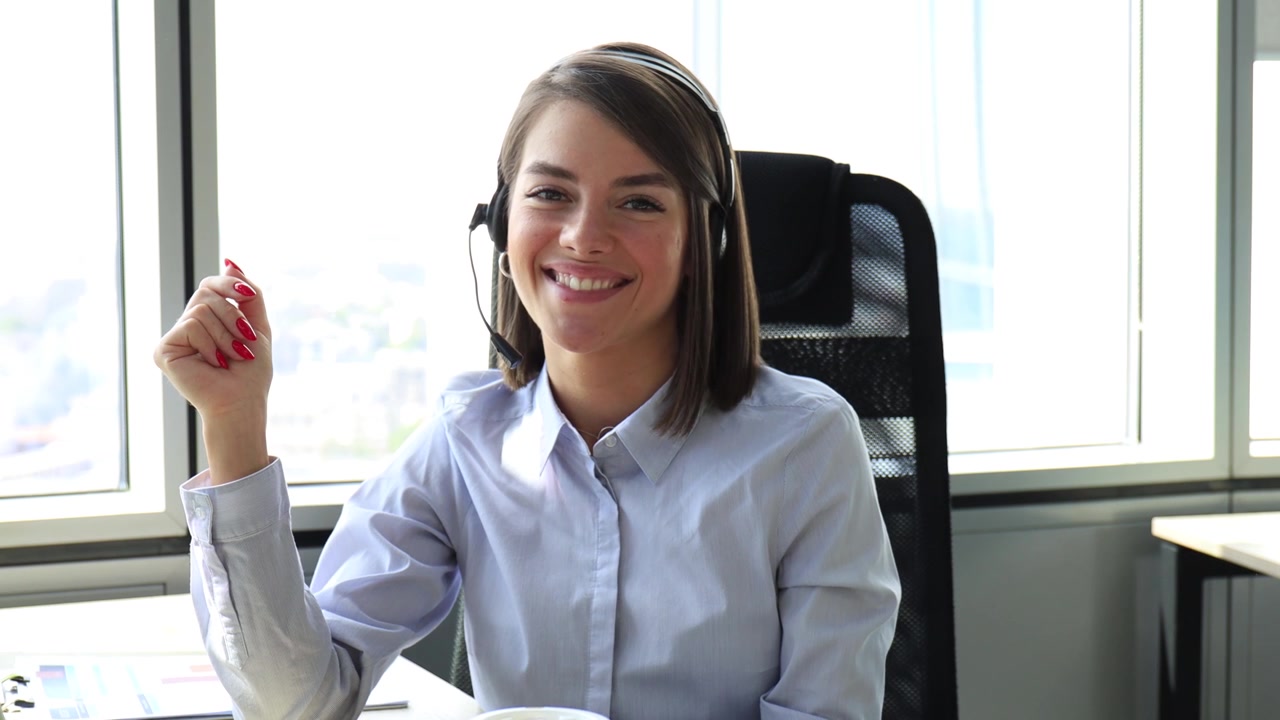 Mulher profissional usando headset, falando e sorrindo no escritório
