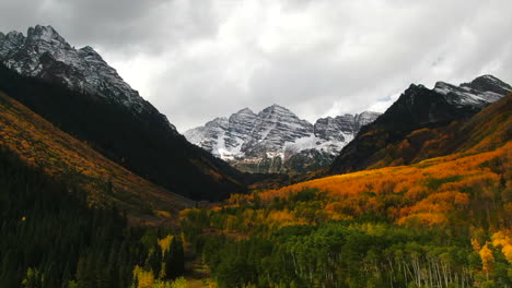 colorful colorado cinematic aerial drone aspen maroon bells capital peak wilderness 14ers autumn fall aspen trees first snow cloudy morning dramatic incredible landscape downward motion