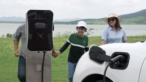 concept of progressive happy family at wind farm with electric vehicle.