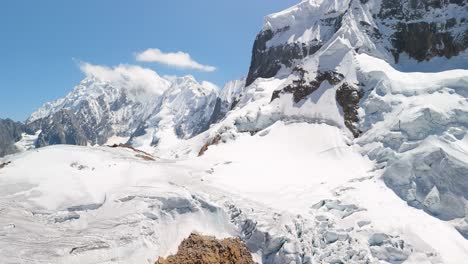 aerial pan and tilt-up shot reveals the majestic, snow-covered summit of a rugged mountain from the trapecio pass on the famous huayhuash trek in peru