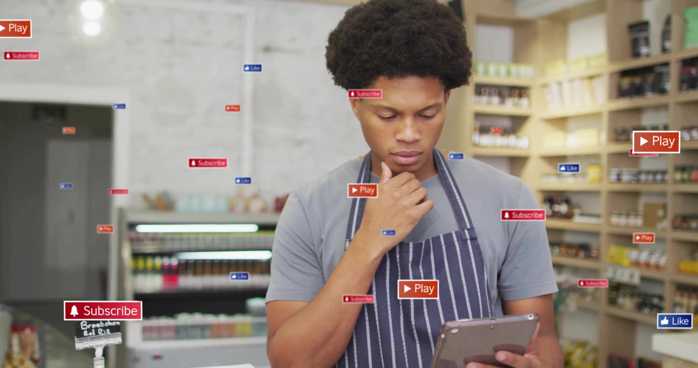 Store clerk tapping tablet checking inventory and generating floating media icons while thinking