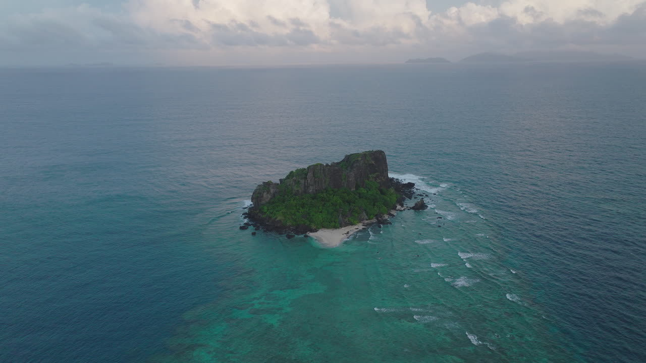 Aerial of small tropical island with visible reef and turquoise ocean below