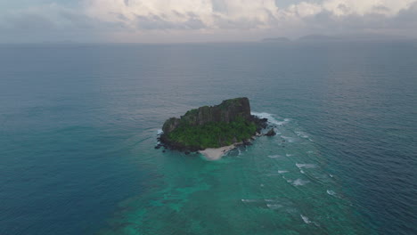 aerial of small tropical island with visible reef and turquoise ocean below