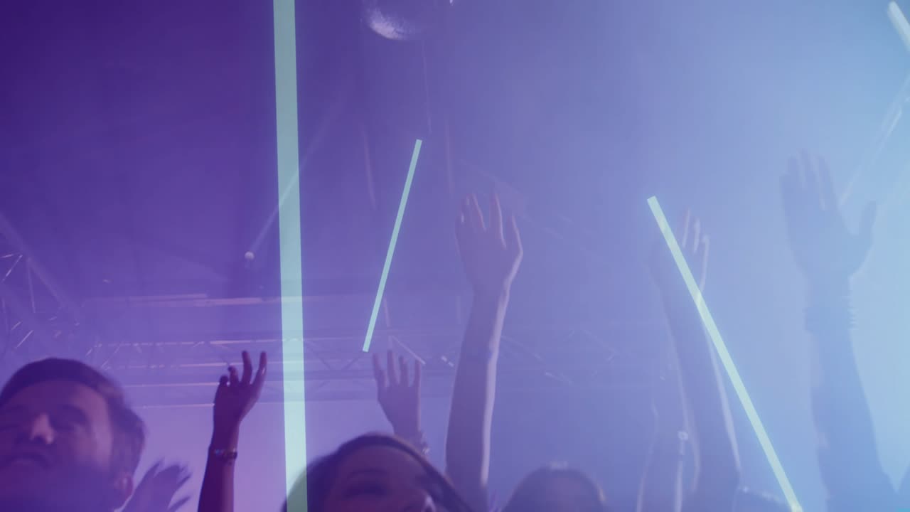 Folla che alza e agita le mani e bastoncini LED dopo che colonne di luce si sono abbassate, celebrando il ritmo