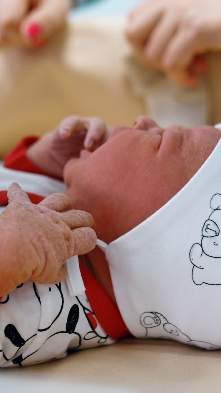 Un tenero neonato giace sul tavolo. Le mani di un medico guantato vestono il bambino. Primo piano. Video verticale.