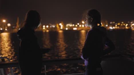 silhouette of two attractive young women traveling on a ship at night. girlfriends on the boat