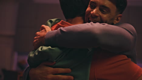 happy friends greeting gathering in evening apartment close up. people hugging