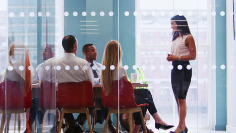 Female-boss-stands-addressing-colleagues-at-business-meeting