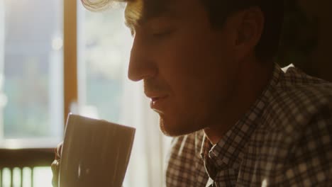 man enjoying a hot drink by the window