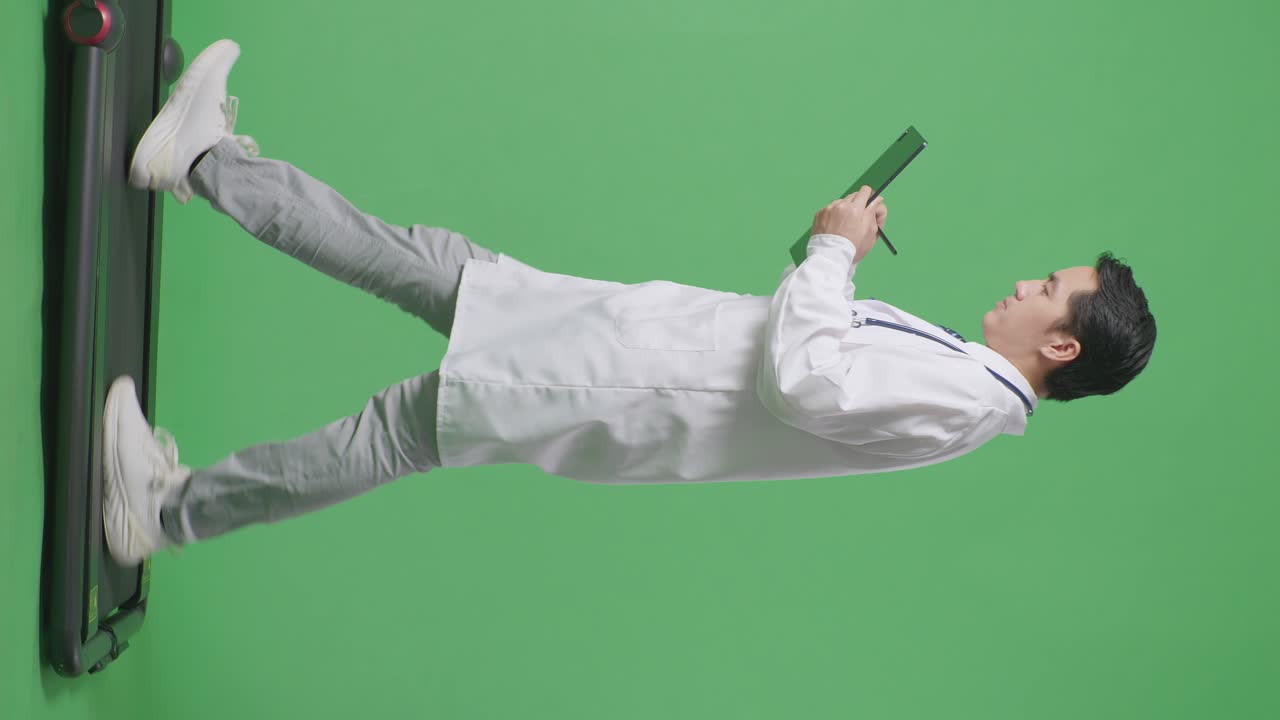 병원에서 녹색 화면 배경에서 는 동안 태블릿에 메모를 취하는 스테토스코프를 가진 아시아 남성 의사