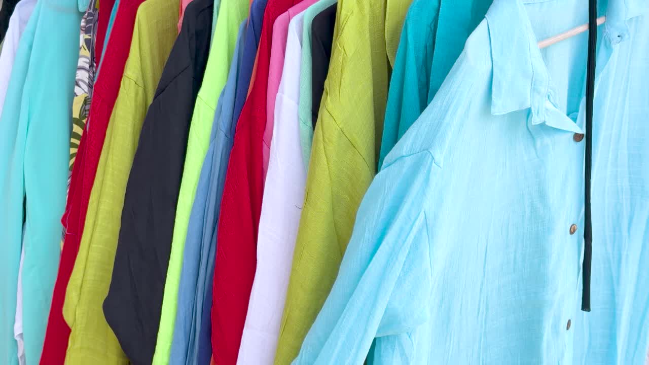 Close-up shot of vibrant linen resort wear hanging on a rack in bright daylight