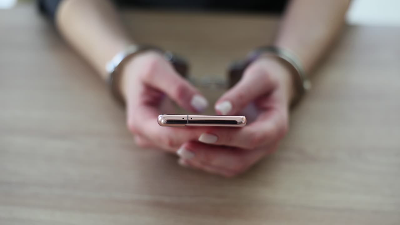 Woman in Handcuffs Using Mobile Phone
