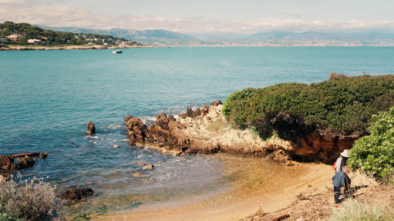 A woman and her child walking near waves crashing on the shore in a secluded spot in Bandol, France