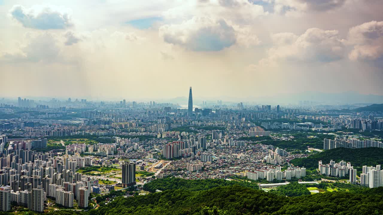 A stunning time-lapse of moving clouds and dramatic light over the sprawling metropolis of Seoul, South Korea, with the iconic Lotte World Tower prominent in the skyline, viewed from Namhansanseong