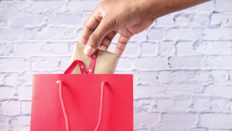 hand placing gift into red shopping bag