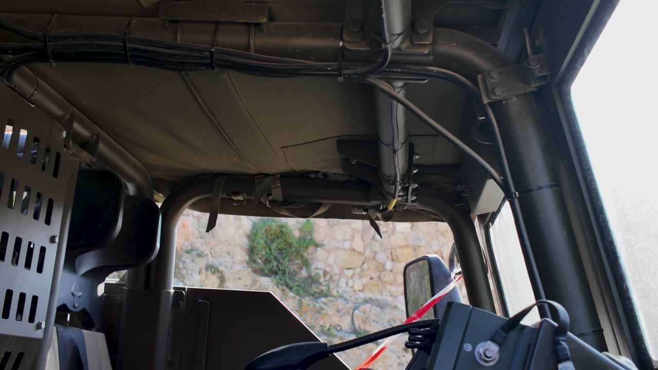 Inside view of military vehicle cockpit showing equipment and reinforced panels