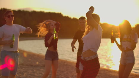 la chica rubia está bailando con la cintura desnuda en la fiesta al aire libre con cerveza. es una fiesta de playa loca y caliente con los mejores amigos de buen humor.