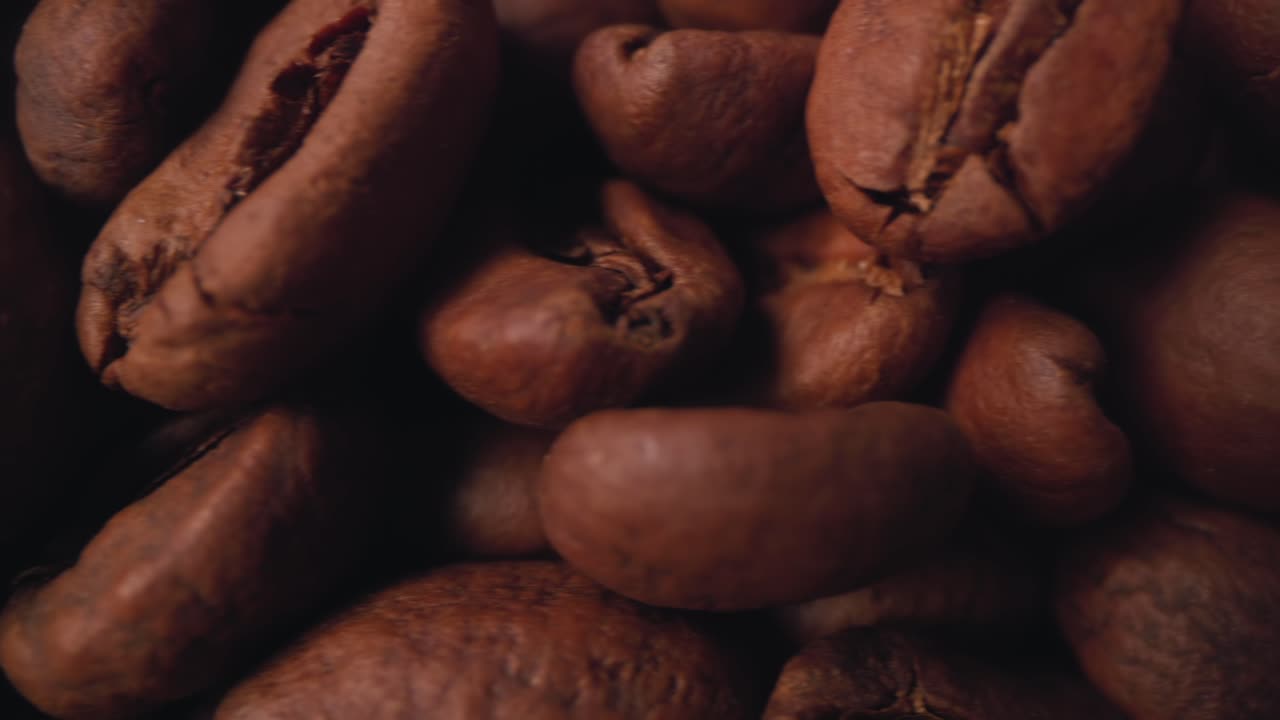 Slow motion Super close up macro slider footage of freshly roasted beans in a pile.