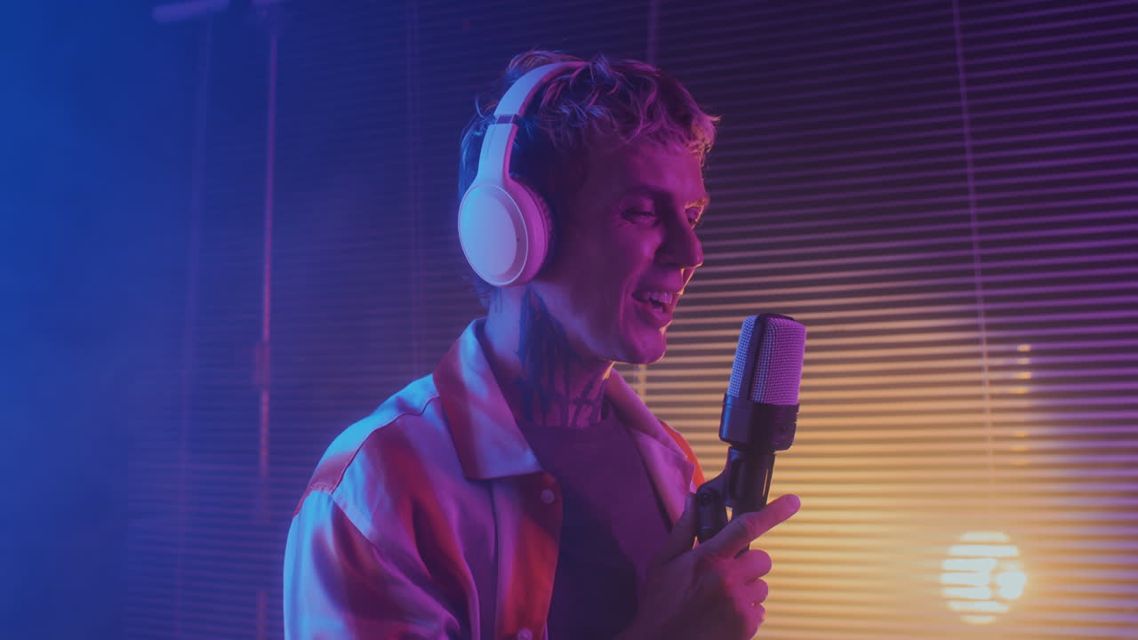 Male Musician Singing in Microphone in Neon Lighting