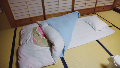리오칸 스타일의 방에서 타타미 매트 위에 있는 전통적인 일본식 푸톤 침대