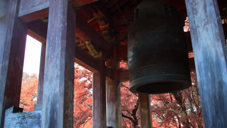 在日本京都的秋季, 一座由<unk>葉樹包圍的日本花園裡的非常古老的鐘,