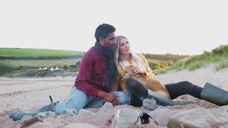 loving couple with dog relaxing by fire on winter beach vacation