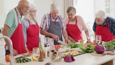 Happy-group-of-diverse-senior-male-and-female-friends-preparing-food-in-kitchen,-slow-motion