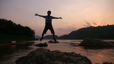 man standing on rocks at sunset by river